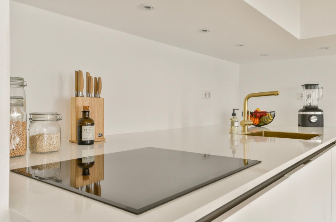 Moderne, minimalistische Küche mit Messerblock, Mixer, goldfarbenem Wasserhahn und Vorratsgläsern