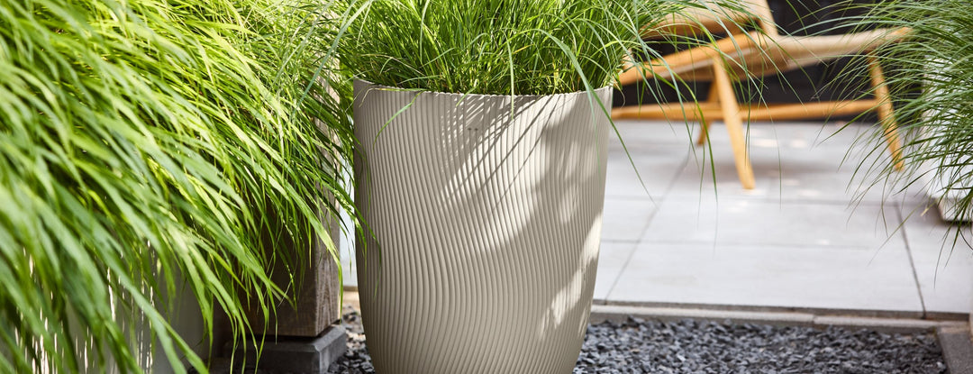 Pot Elho Sereh beige avec des graminées sur une terrasse