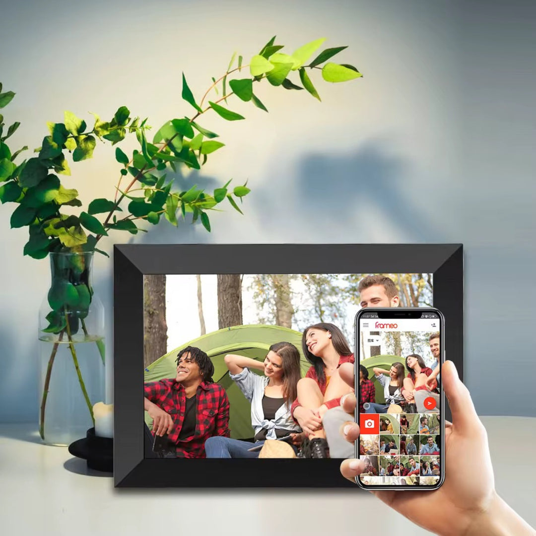 Cadre photo numérique Frameo noir sur la table, smartphone avec l'app en main