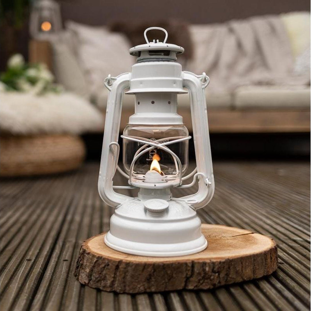 Feuerhand Sturmlaterne Baby Special 276, Pure White auf Holzscheibe auf der Terrasse