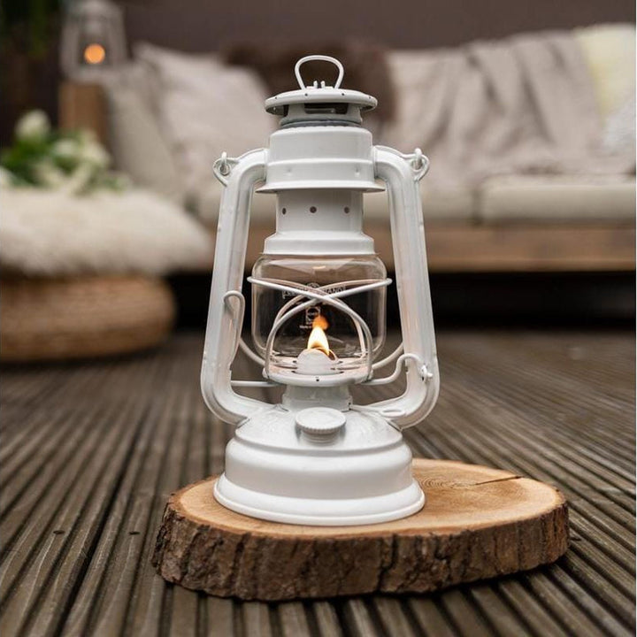 Feuerhand Sturmlaterne Baby Special 276, Pure White auf Holzscheibe auf der Terrasse