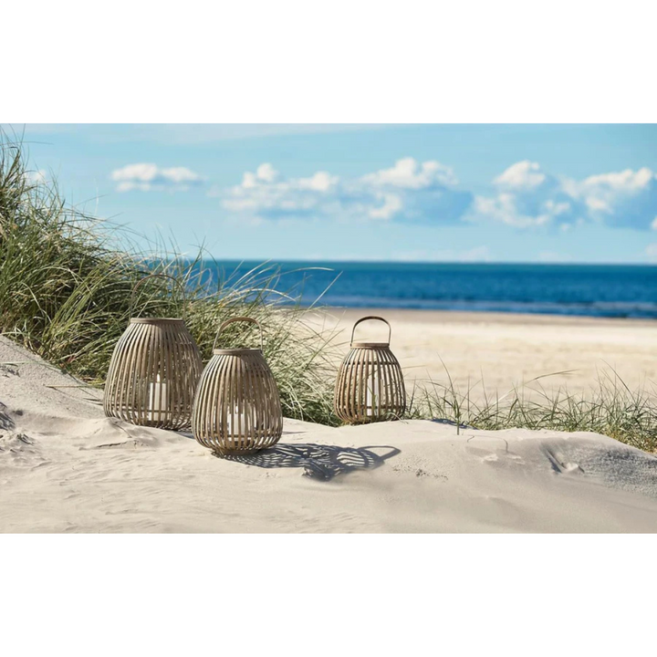 Drei Bambus-Laternen mit Kerzen in den Dünen am Strand