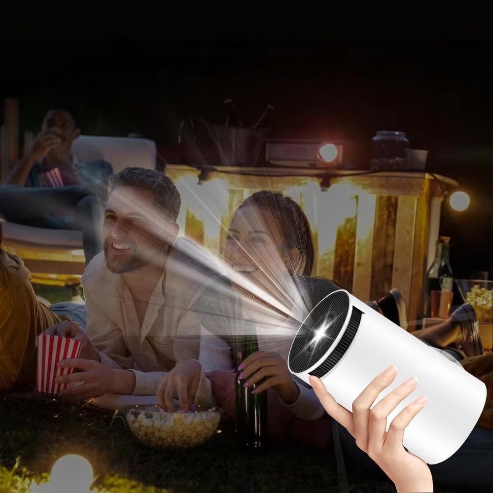 Mini Beamer LED in der Hand bei einem Filmabend im Garten