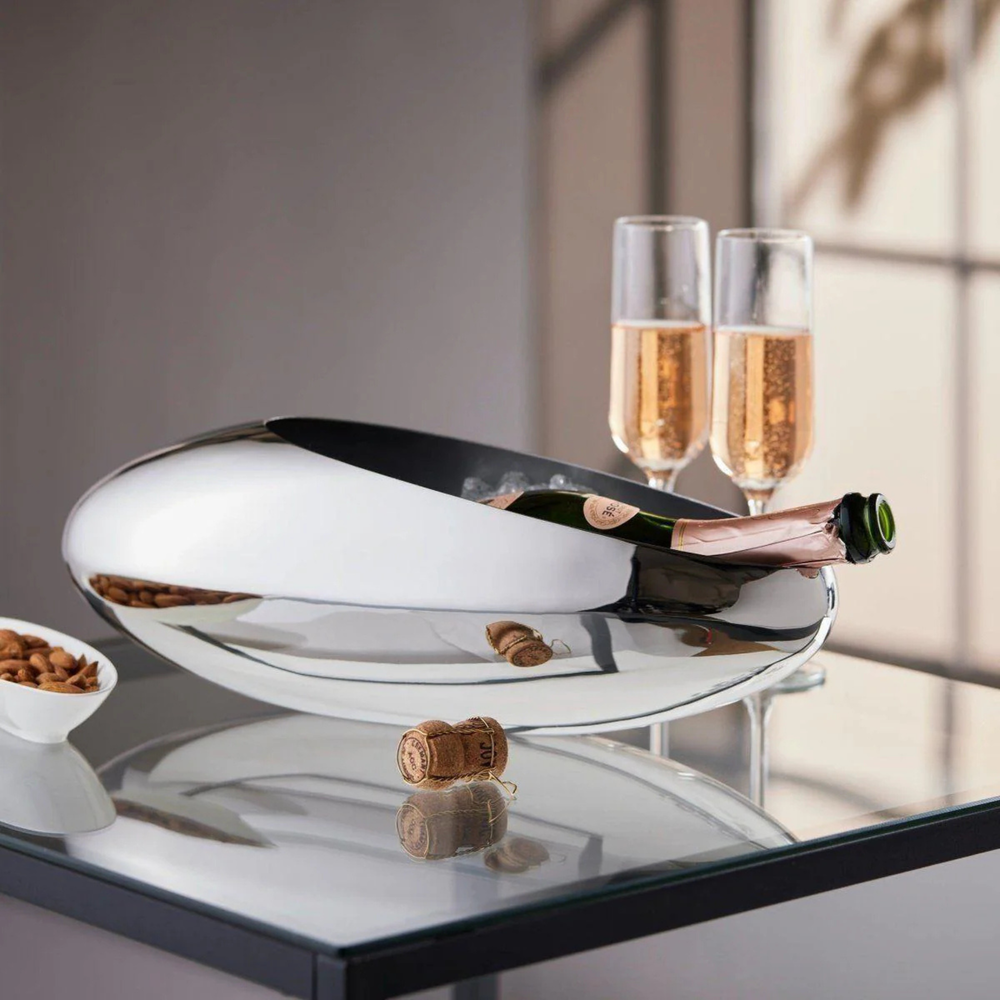 Philippi Cocoon Champagnerkühler aus Edelstahl auf Tisch mit Champagnergläsern im Hintergrund