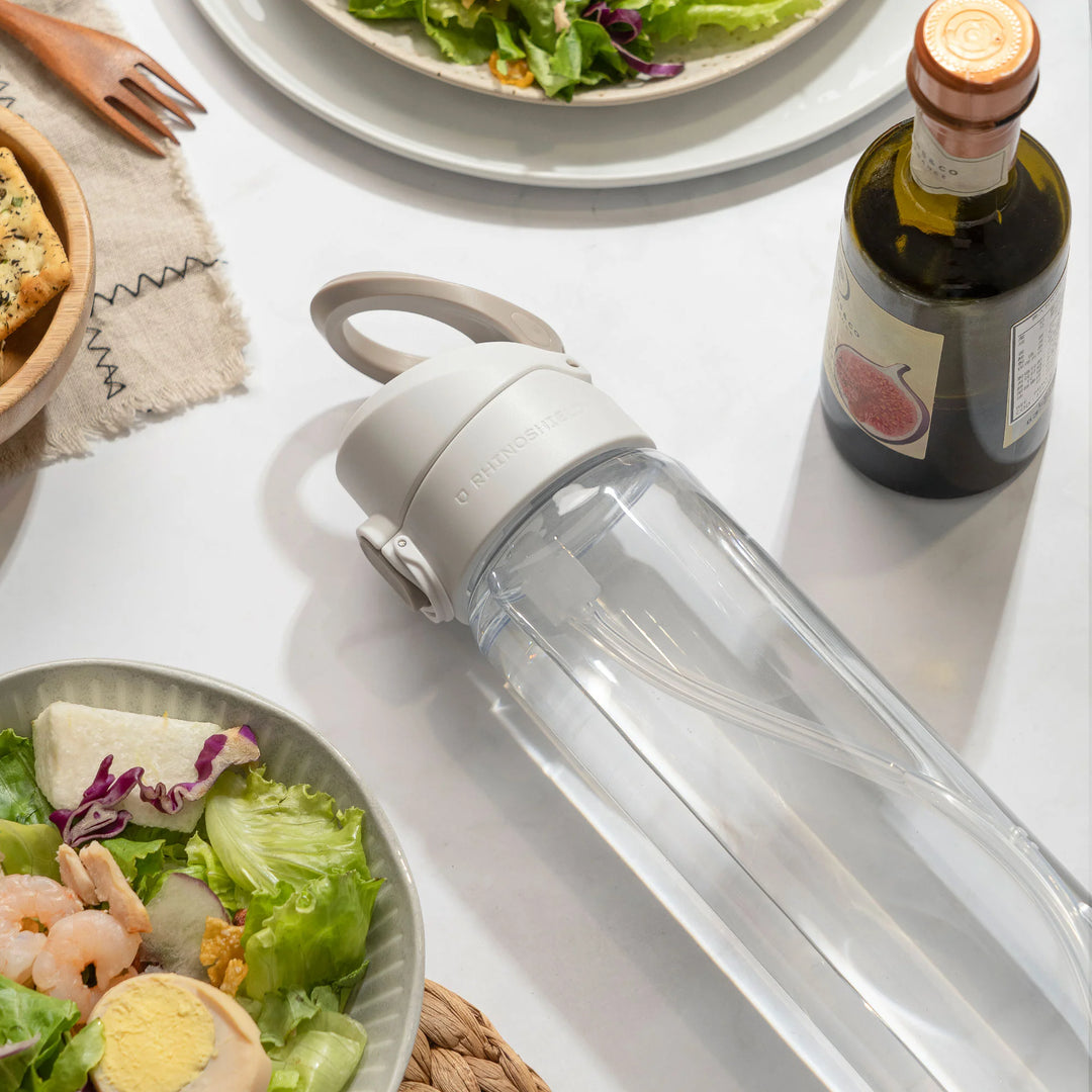 Weisser AquaStand liegt auf einem gedeckten Tisch neben Salat und Olivenöl