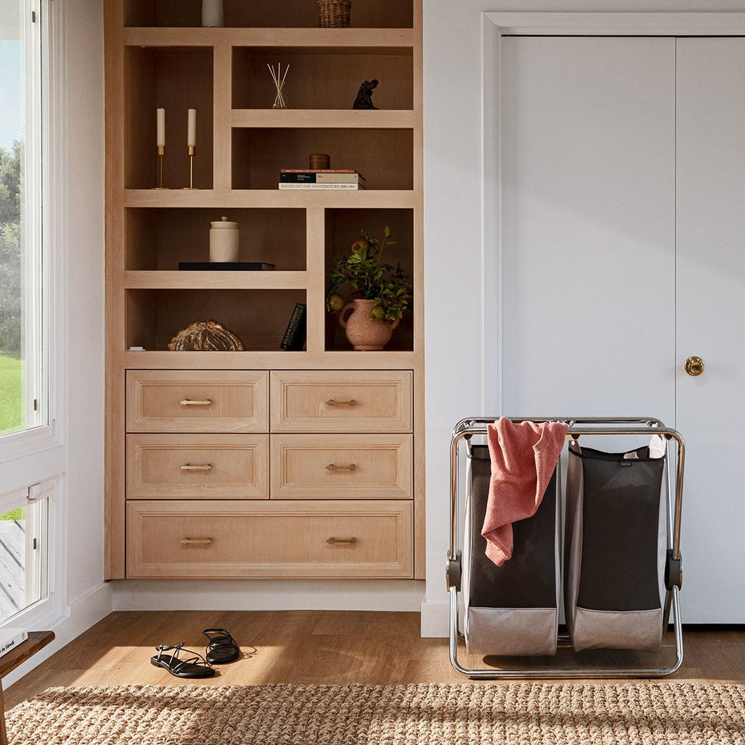 Panier à linge Simplehuman à cadre en X dans un dressing devant une armoire encastrée
