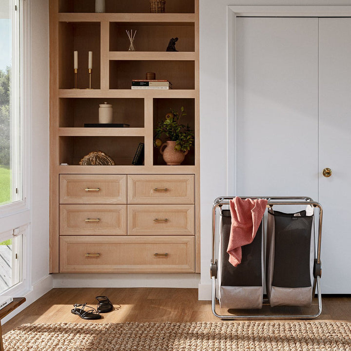 Panier à linge Simplehuman à cadre en X dans un dressing devant une armoire encastrée