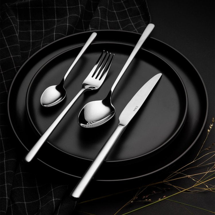 Ménagère Sola Calgary, couteau, fourchette et deux cuillères sur une assiette noire