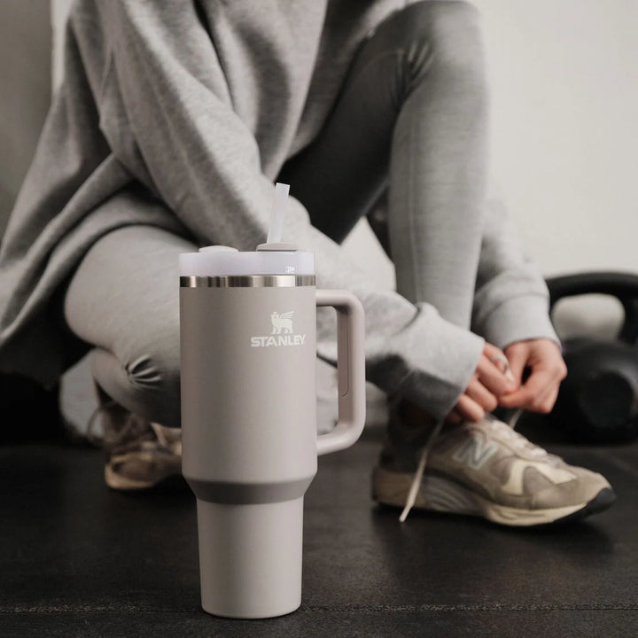 Stanley Quencher H2.0 auf dem Boden im Fitnessstudio neben Sportschuhen