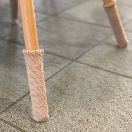 Chaussettes de chaise Uni, beige, sur un pied de chaise en bois sur carrelage