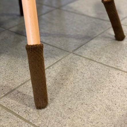 Chaussettes de chaise Uni, brun, sur un pied de chaise en bois sur carrelage