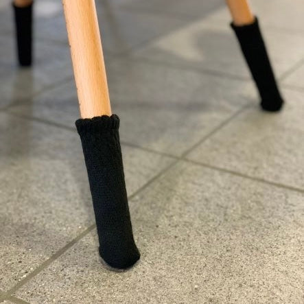 Chaussettes de chaise Uni, noir, sur un pied de chaise en bois sur carrelage