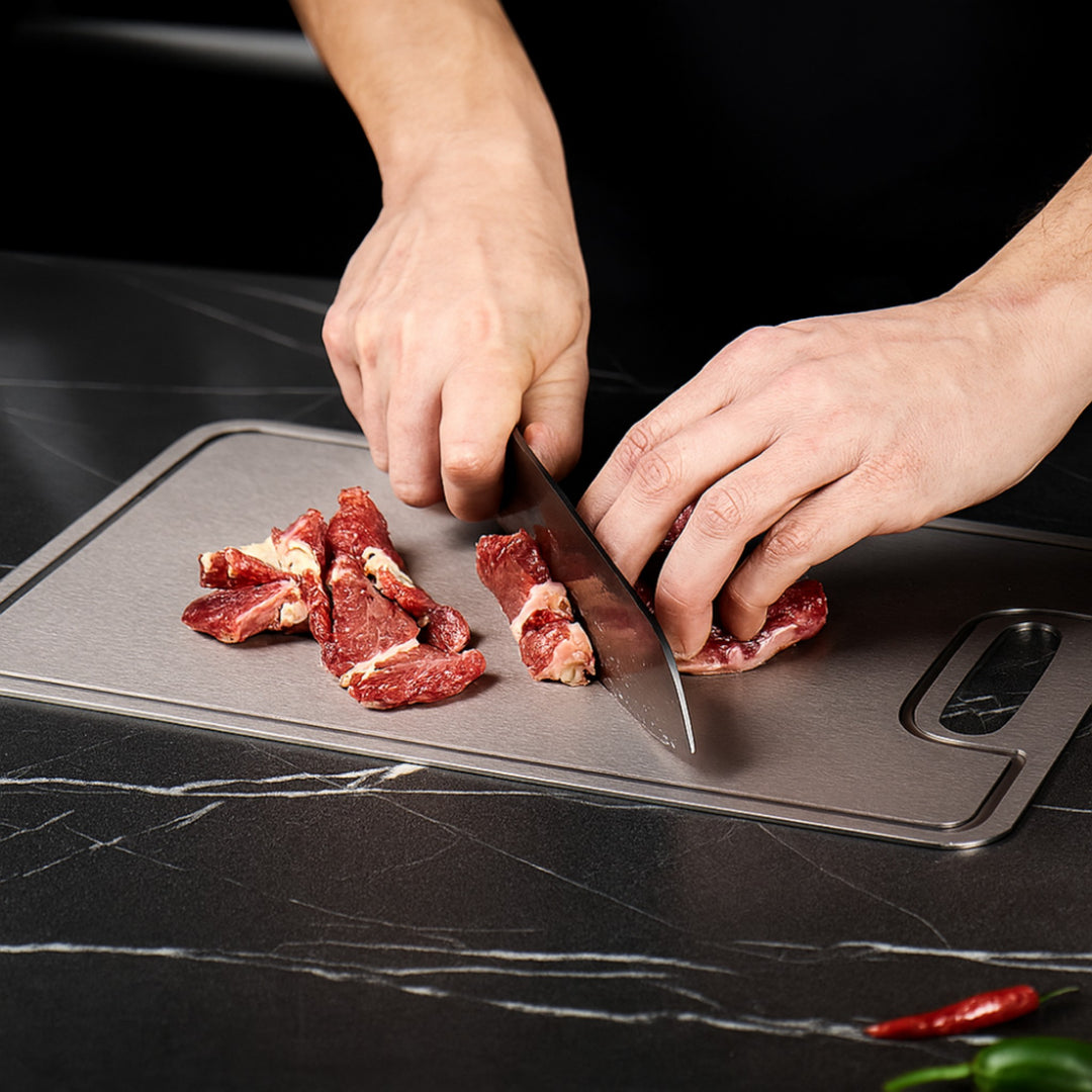 Titan-Schneidebrett beim Schneiden von Rindfleisch auf dunklem Marmor