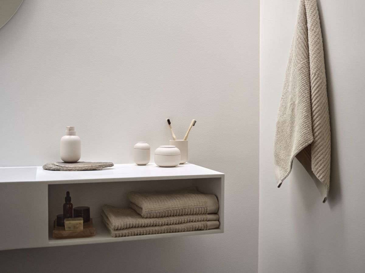 Weisser Waschtisch mit Badaccessoires aus Keramik und Handtüchern in Beige