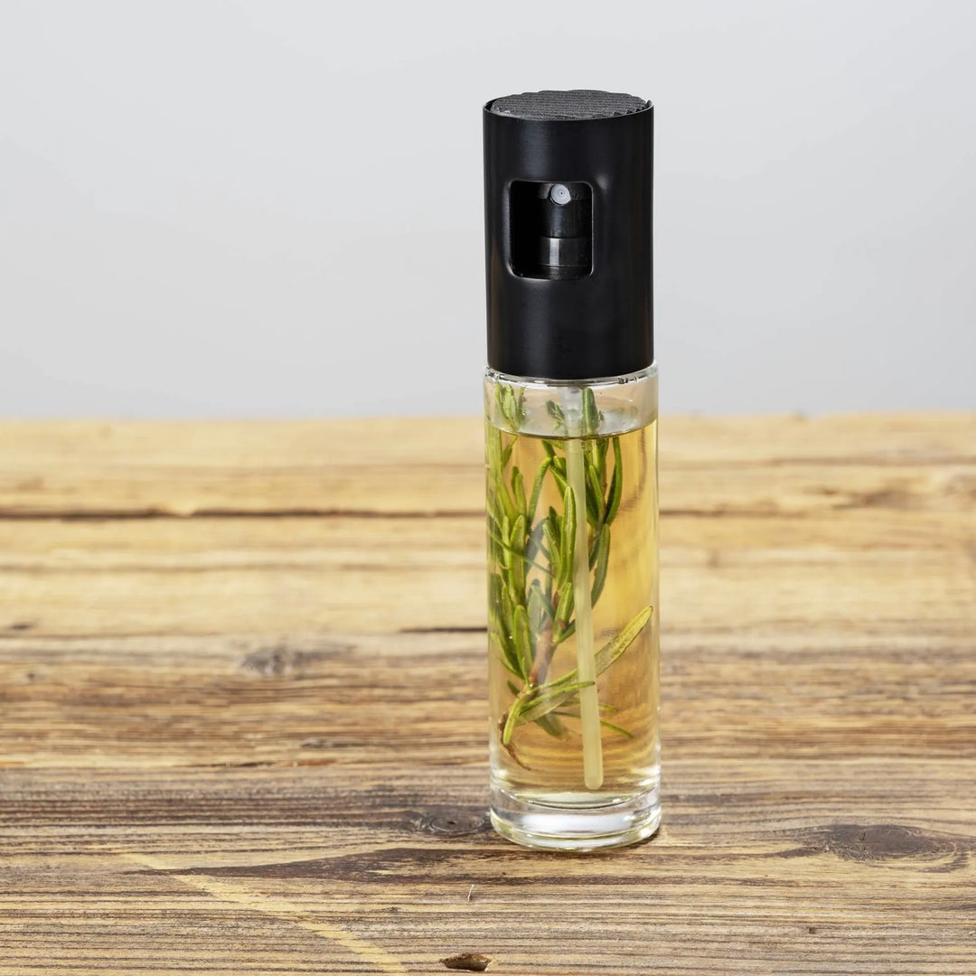 Vaporisateur à huile et vinaigre Wenko Nevo 100 ml, avec un brin de romarin sur une table en bois